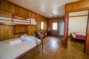Mana Backpackers and Dive Resort في جزيرة مانا: غرفة نوم بسريرين بطابقين وغرفة معيشة