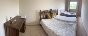 a bedroom with a large bed and a wooden desk at Kitnet ao lado do centro in Itabira