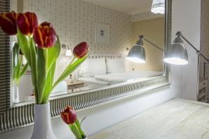 a vase with red flowers in front of a mirror at Hotel Pod Bránou in Bardejov +37 photos
