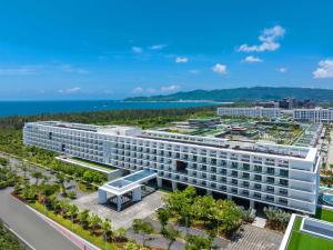 Sanya Haitang Bay Moutai Resort Superior Hotel في سانيا: اطلالة جوية على فندق مع المحيط في الخلفية