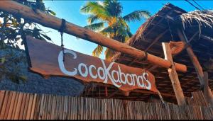 a cocacola sign hanging from a wooden fence at CocoKabanasRote in Nembrala