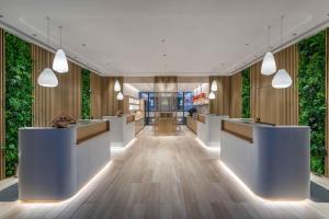 a lobby with white reception desks and plants at Sanya Haitang Bay Moutai Resort Classic Hotel in Sanya