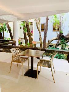 a wooden table and two chairs in a room with trees at White House Beach Resort in Boracay