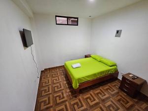 a bedroom with a green bed and a television at Departamento de Jules in Puerto Ayora