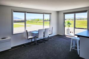 una oficina con mesa, sillas y ventanas en Glen View Escape en Twizel