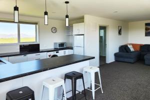 cocina y sala de estar con encimera y taburetes en Glen View Escape en Twizel