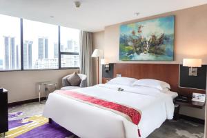ein Hotelzimmer mit einem großen weißen Bett und Fenstern in der Unterkunft The Pavilion Century Tower (Huaqiang NorthBusiness Zone) in Shenzhen
