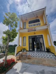 une maison jaune avec une table devant elle dans l'établissement Quê hương Villa (Indochine Villas Tam Chau), à Bảo Lộc