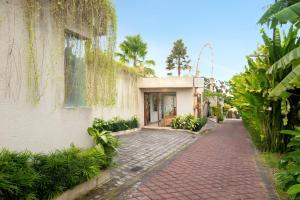 a brick sidewalk next to a building with plants at Manca Villa Canggu by Ini Vie Hospitality in Canggu