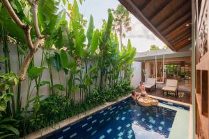a swimming pool with a person in a raft in a backyard at Manca Villa Canggu by Ini Vie Hospitality in Canggu