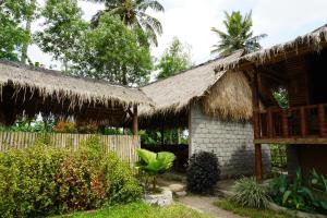 a house with a thatched roof and a fence at New Rinjani Homestay in Tetebatu