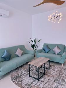 Sala de estar con 2 sofás verdes y mesa de centro en The Halt Putrajaya, en Putrajaya