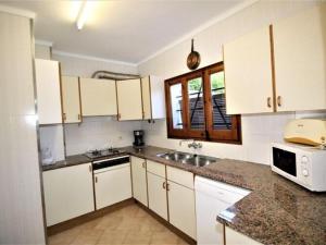 a kitchen with white cabinets and a sink at Apartments La Pineda, Playa de Pals in Begur