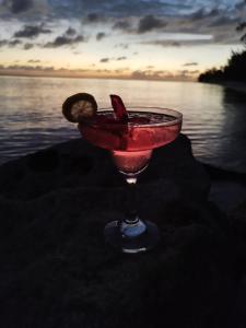 a red drink sitting on the sand near the water at Beach Villas in Nassau