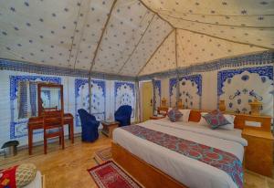 a bedroom with a bed and a desk in a room at Sam Sand Dunes Jaisalmer in Jaisalmer