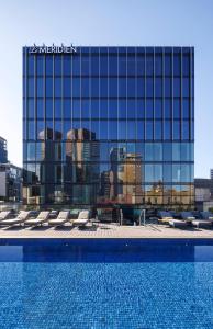 a hotel with a swimming pool in front of a building at Le Méridien Melbourne in Melbourne