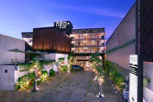 a hotel building with a parking lot in front of it at Hotel NEO+ Kuta Legian by ASTON in Legian