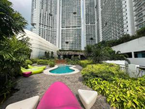 a garden with pink and green chairs and a pool at Sakura House in Manila
