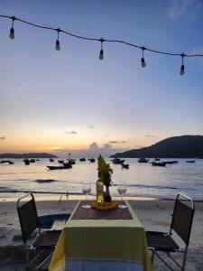 una mesa con copas de vino en una playa con el océano en Monkey Homestay & Bar en Tân Hiệp