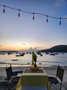 a table with wine glasses on a beach with the ocean at Monkey Homestay & Bar in Tân Hiệp