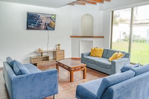 a living room with two blue couches and a table at Casa Tipo Chalet especial Grupos grandes in Bogotá