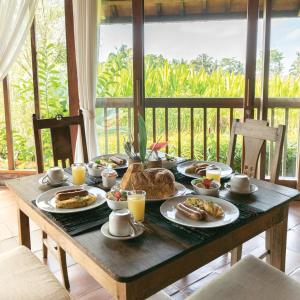 una mesa de madera con productos para el desayuno en Ayawana Private Villas Managed by ARM Hospitality, en Tegalalang