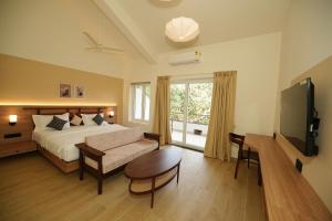 a bedroom with a bed and a couch and a tv at Anjuna Beach Resort in Anjuna
