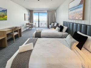 a hotel room with two beds and a desk at Direct Collective - Bli Bli Suites in Bli Bli