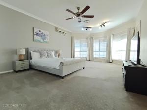 a white bedroom with a bed and a ceiling fan at Hunter Valley Nulkaba breathtaking views relax in Nulkaba