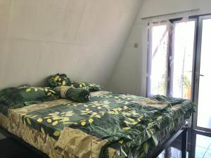a bedroom with a bed with a green and yellow comforter at Villa Eger Rinjani in Sembalun Lawang