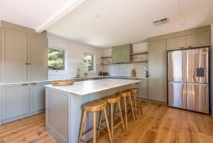 cocina con armarios blancos, nevera y taburetes en The Residence at Schubert Estate en Nuriootpa