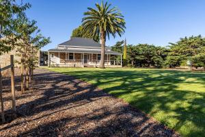 a house with a palm tree in front of a yard at The Residence at Schubert Estate in Nuriootpa