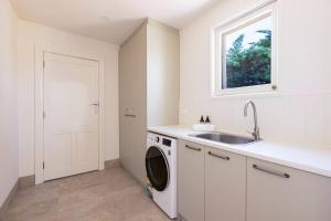 uma cozinha branca com um lavatório e uma máquina de lavar roupa em The Residence at Schubert Estate em Nuriootpa
