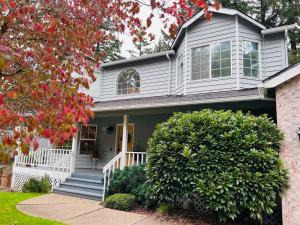 een grijs huis met een witte veranda en een boom bij Sopra Bella- 4 bedroom home in Corvallis