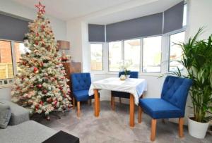 a christmas tree in a living room with a table and blue chairs at Greenfields Spa with private hottub New listing in Malvern Link