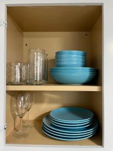 a cupboard with plates and glasses and plates and bowls at Private studio near Green Lake/Lightrail/I-5 in Seattle