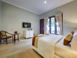 a bedroom with two beds and a table and a tv at U Tube Hotel in Uluwatu