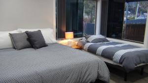 Un dormitorio con dos camas y una ventana. en East Coast Hideaway Beach Retreat, en Orford