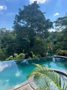 a woman standing next to a swimming pool in a forest at Ubud Dedari Villas in Ubud