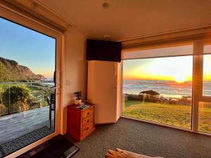 a room with large windows with a view of the ocean at View With A Room NZ - Boutique Beachfront Accommodation on the Great Coast Road in Runanga