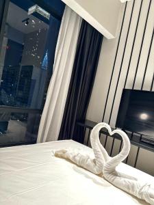 Axon Residence By Leo Suites في كوالالمبور: سرير أبيض عليه منشفة على شكل قلب