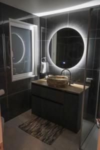 a bathroom with a sink and a round mirror at View With A Room NZ - Boutique Beachfront Accommodation on the Great Coast Road in Runanga