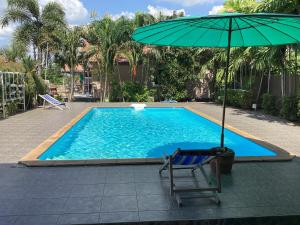 a blue swimming pool with a chair and an umbrella at Oh taley resort in Rayong
