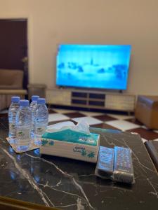 a table with bottles of water and a remote control at Mountain house in Al-ʿUla