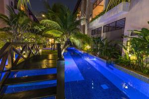 een zwembad met een palmboom naast een gebouw bij Bali Hotel in Phnom Penh
