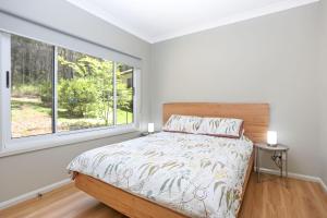 a bedroom with a bed and a large window at Wylah in North Arms Cove
