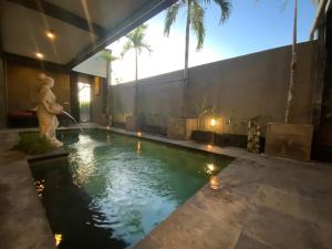 a swimming pool in a house with a fountain at Bali Golden Elephant Boutique Villa in Jimbaran