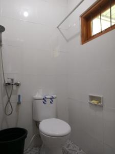 ein weißes Bad mit einem WC und einem Fenster in der Unterkunft umah kampung bendul in Penebel