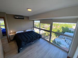 een slaapkamer met een bed en een groot raam bij Departamento de Película in Mendoza