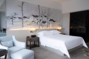 a bedroom with a large white bed and a chair at Huaqiang Plaza Hotel Shenzhen, Enjoy Complimentary Mini Bar & Night Snack, Add breakfast - enjoy complimentary afternoon tea in Shenzhen